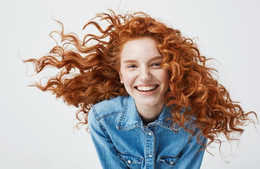 Junge Frau mit roten Locken lacht.