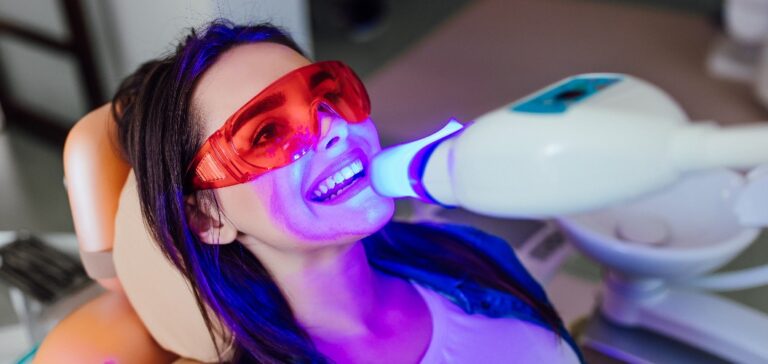 Frau mit Schutzbrille hat Zahn-Bleaching-Behandlung